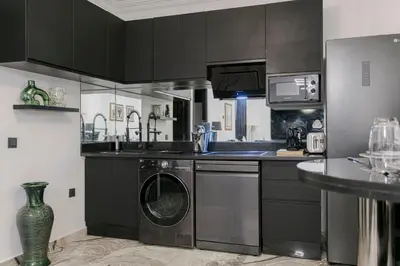 a kitchen with black cabinets and a washer at A Stay To Remember - Marrakech Downtown in Marrakech