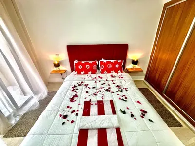 a bed with red pillows and flowers on it at Appartement à louer in Marrakech