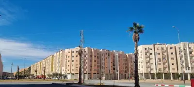 a tall building with a palm tree in front of it at Cozy appartement à Marrakesh in Marrakech