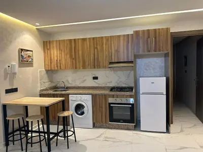 a kitchen with wooden cabinets and a table with stools at Spacieux Appartement avec terrasse coeur de Marrakech in Marrakech