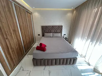 a bedroom with a large bed with a red pillow on it at Spacieux Appartement avec terrasse coeur de Marrakech in Marrakech