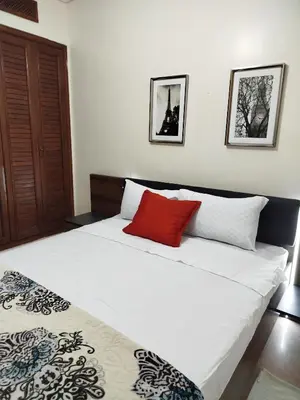 a bedroom with a large white bed with a red pillow at charmant appartement avec grande piscine & terrasse in Marrakech