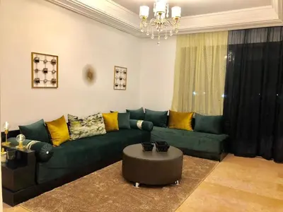 a living room with a green couch and a table at charmant appartement avec grande piscine & terrasse in Marrakech