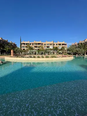 a large body of water with a building in the background at charmant appartement avec grande piscine & terrasse in Marrakech