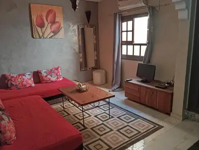 a living room with a red couch and a table at appartement 6 min centre terrasse in Marrakech