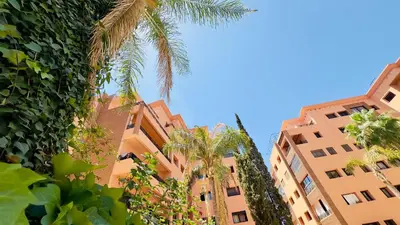 two tall buildings with palm trees in front of them at - Résidence Babylone Y - 1 Bedroom Appartement in Marrakech