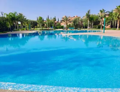 a large pool of blue water with palm trees at Havre de paix à Atlas Golf Resort Marrakech in Marrakech