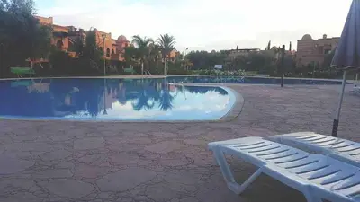 a white chair next to a swimming pool with avisorvisor at Havre de paix à Atlas Golf Resort Marrakech in Marrakech