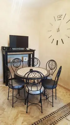 a table and chairs with a clock on the wall at Havre de paix à Atlas Golf Resort Marrakech in Marrakech