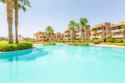 a large swimming pool with palm trees and buildings at Appartement 3 Chambres in Marrakech