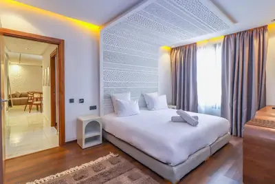 a bedroom with a large white bed and a living room at Jnane Guéliz 2CH parking wifi Marrakech centre in Marrakech