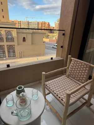 a balcony with a table and a chair and a window at Jnane Guéliz 2CH parking wifi Marrakech centre in Marrakech