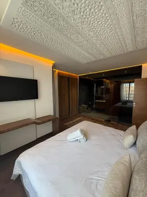 a bedroom with a large white bed with a flat screen tv at Jnane Guéliz 2CH parking wifi Marrakech centre in Marrakech