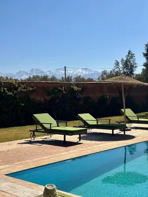 a group of green lounge chairs and a swimming pool at NEW Dar Aït Zahra Marrakech-Cook included-View ATLAS in Marrakech