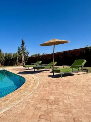 a group of benches with an umbrella and a pool at NEW Dar Aït Zahra Marrakech-Cook included-View ATLAS in Marrakech