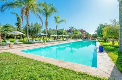 a swimming pool at a resort with palm trees at Appartement moderne et chic, avec piscine pour femmes et Parc de jeux in Dar Caïd Layadi