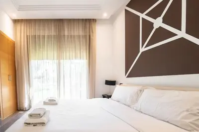 a bedroom with a large white bed with towels on it at Appartement moderne et chic, avec piscine pour femmes et Parc de jeux in Dar Caïd Layadi