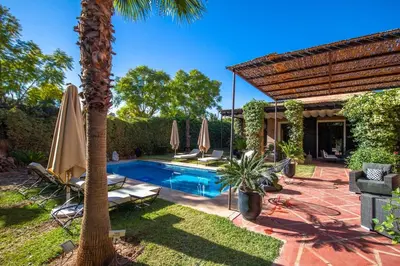 a backyard with a swimming pool with umbrellas at Amelkis golf villa 3 ch private pool in Marrakech