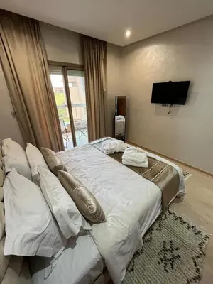 a bedroom with a large white bed with a flat screen tv at Appartement de luxe prestigia agate Marrakech in Marrakech