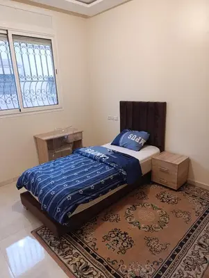 a bedroom with a bed with a blue comforter and a rug at Excellente appartement 3 chambres in Marrakech