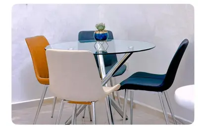 a glass table with four chairs and a vase on it at Spacious apartment in Marrakech in Marrakech