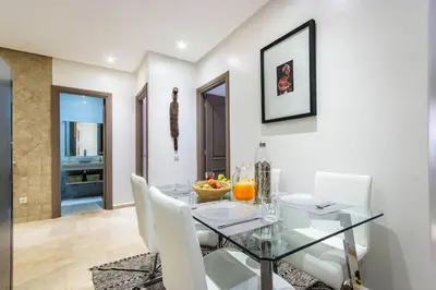 a dining room with a glass table and white chairs at Au coeur Hivernage Proche M avenue in Marrakech