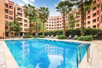 a swimming pool with palm trees and a building at Au coeur Hivernage Proche M avenue in Marrakech