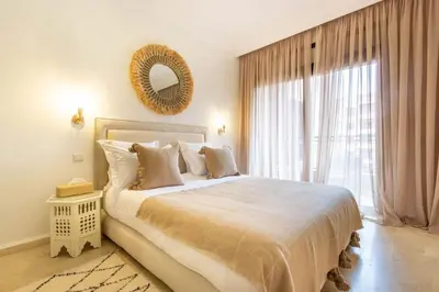 a bedroom with a large bed with a mirror and a window at Au coeur Hivernage Proche M avenue in Marrakech