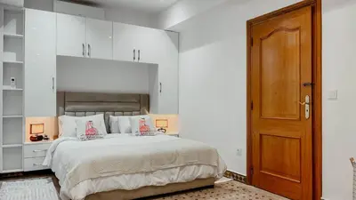 a bedroom with a large bed and a wooden door at Appartement 1ch Hivernage avec Piscine in Marrakech