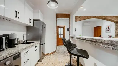 a kitchen with white cabinets and a black chair in it at Appartement 1ch Hivernage avec Piscine in Marrakech