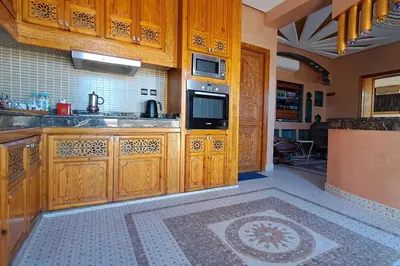 a kitchen with wooden cabinets and a tile floor at Cozy, sunny apartment near the airport in Marrakech