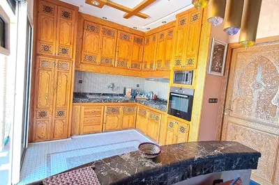 a kitchen with wooden cabinets and a counter top at Cozy, sunny apartment near the airport in Marrakech