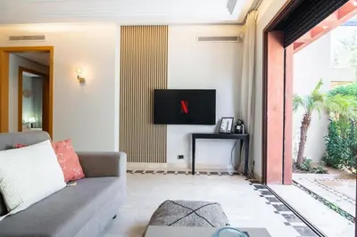 a living room with a couch and a tv at Appartement Cosy avec Parc et Piscine pour femme in Marrakech