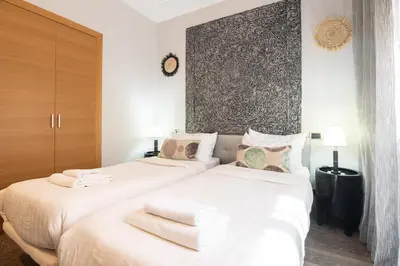 two white beds in a bedroom with a wall at Appartement Cosy avec Parc et Piscine pour femme in Marrakech