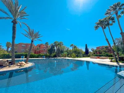 a large swimming pool with palm trees and buildings at Modern Apartment in a Resort Luxury and Comfort in Marrakech