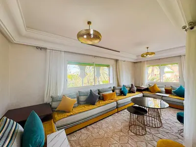 a living room with a long couch with yellow and blue pillows at Luxurious Duplex in a Peaceful Resort in Marrakech in Marrakech