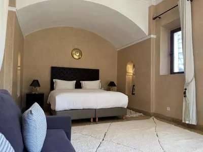 a bedroom with a large bed and a couch at Villa Hilin - Piscine chauffée et hammam privé proche des golfs et du centre ville in Marrakech