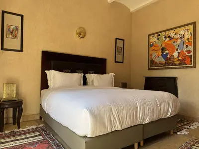a bedroom with a large bed with white sheets at Villa Hilin - Piscine chauffée et hammam privé proche des golfs et du centre ville in Marrakech