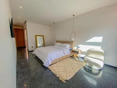a bedroom with a bed and a chair and a mirror at Villa Warda Luxe & Confort in Marrakech