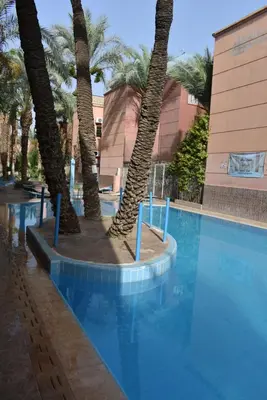a swimming pool with palm trees next to a building at Apartment A Zaitone G19 in Marrakech