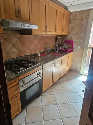 a kitchen with wooden cabinets and a stove top oven at Appartement de luxe Résidence Majorelle in Marrakech