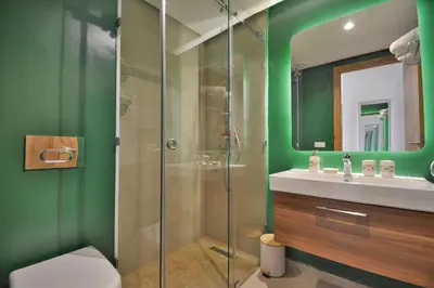 a green bathroom with a shower and a sink at Appartement Domaine de Noria 7 in Marrakech