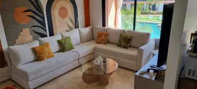 a living room with a white couch and a glass table at Appartement Domaine de Noria 7 in Marrakech