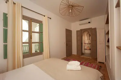 a white bedroom with a bed and a window at Riad Deva Lina in Marrakech