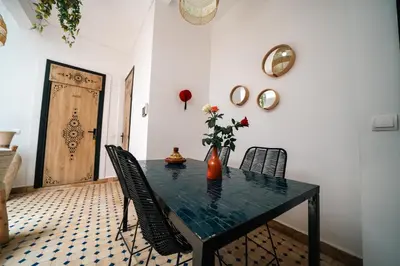 a dining room with a table with chairs and a vase with flowers at Riad Le Soleil de Bahia in Marrakech