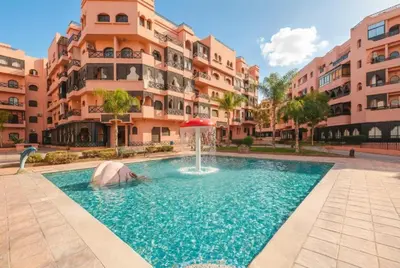 a pool with a fountain in front of a building at Bel Appartement Vue Piscine in Marrakech