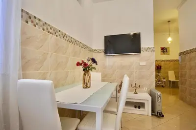 a dining room with a white table and a tv on a wall at Gold Holidays 02 in Marrakech