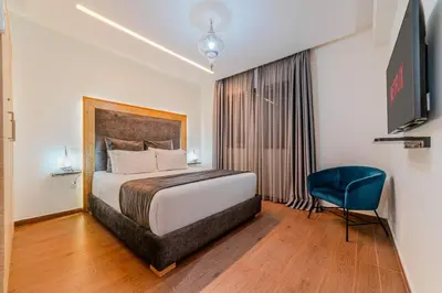 a hotel room with a bed and a blue chair at Coralia - Cozy Apartment - Secure residence - Pool in Marrakech