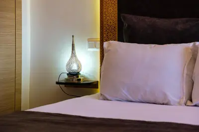 a bed with a white pillow and a lamp on a table at Coralia - Cozy Apartment - Secure residence - Pool in Marrakech