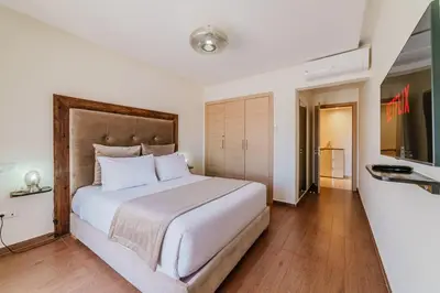 a bedroom with a large white bed and a television at Coralia - Cozy Apartment - Secure residence - Pool in Marrakech
